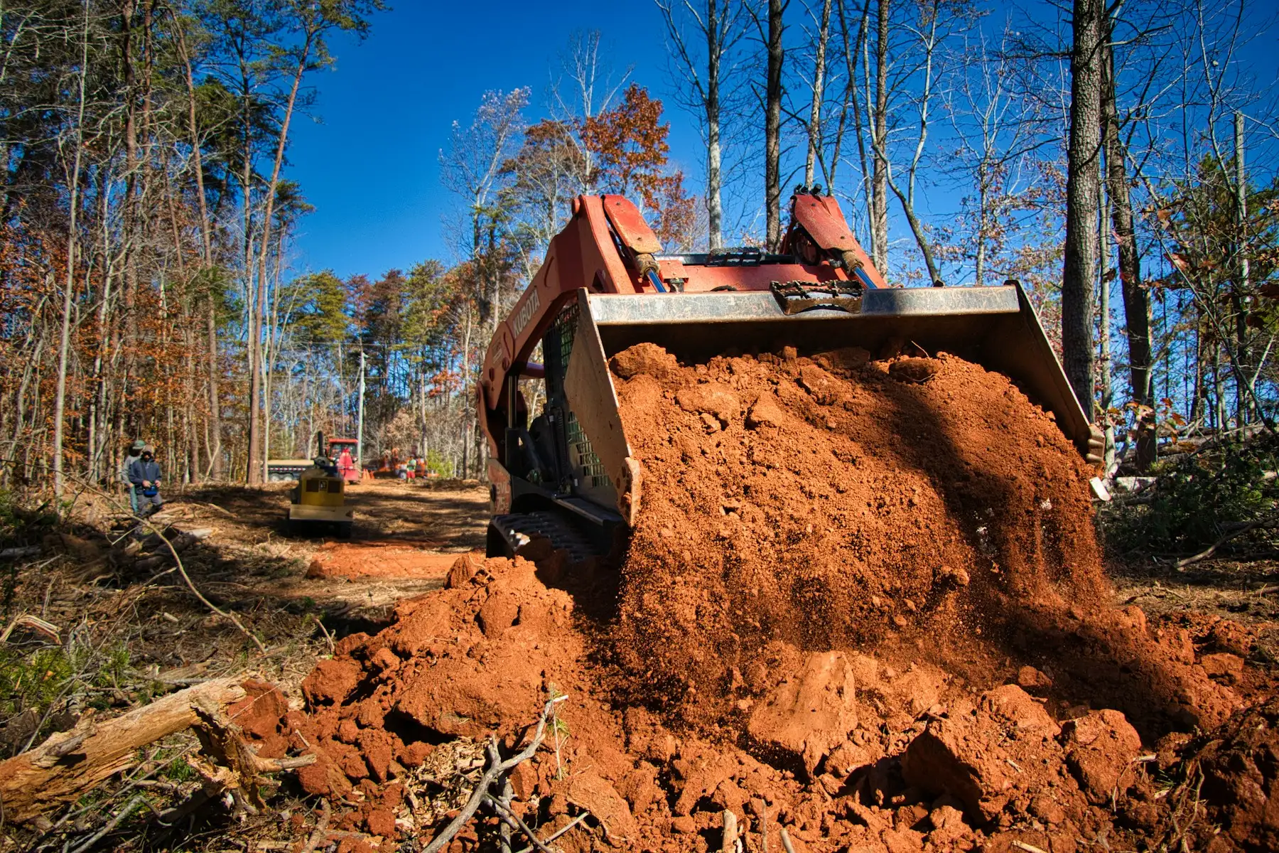 Dozer blade pushing red clay while grading a cleared site