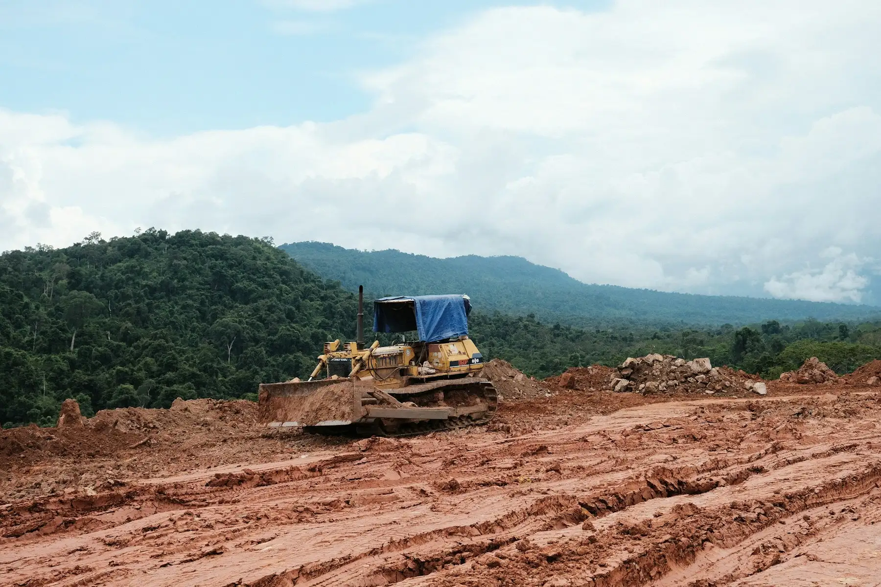 Bulldozer shaping a dirt building pad on a cleared construction site